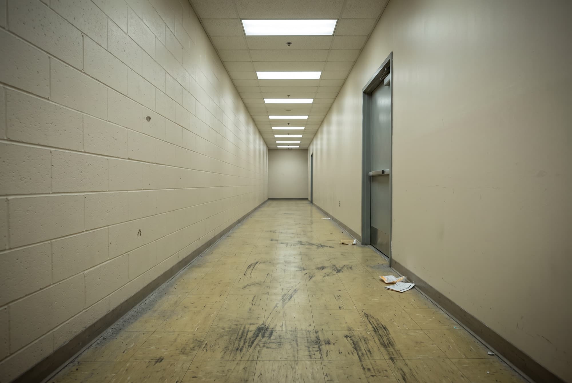 A commercial corridor floor before cleaning, dull and heavily scuffed